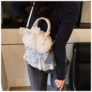 Detail of creamy white mini Boston bag with embossed cartoon patterns and lace bow