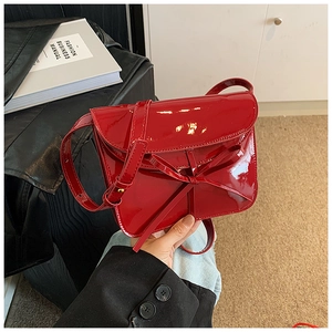 Macro shot of red patent leather envelope bag with delicate bow and glossy finish