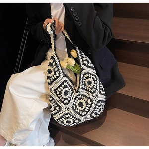 Detail of a handmade crochet hobo bag with retro black and white floral pattern