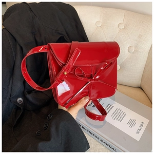 Detail of red oil wax leather shoulder bag with chic bow and glossy mirror finish