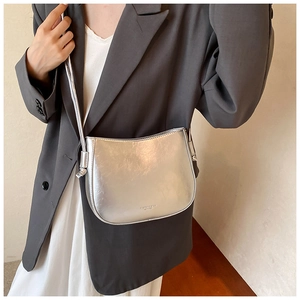 Dettaglio della borsa a sella argento metallizzato con texture spazzolata su una modella