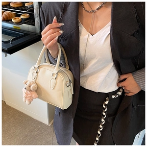 Close-up of beige lychee texture bowling bag with cute bear charm in bakery setting
