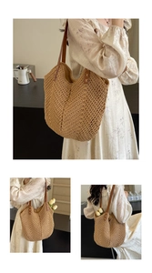 Detail of woven straw tote bag with brown leather straps and cross-stitch accents