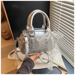 Detailed macro of silver Boston bag featuring embossed heart patterns and lace bow decor