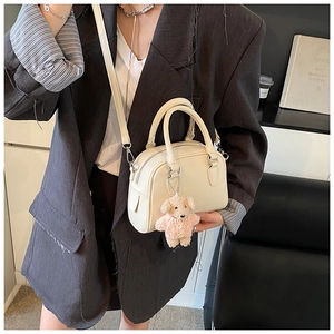 Detail of cream white pebbled leather bowling bag with cute puppy plush charm accessory