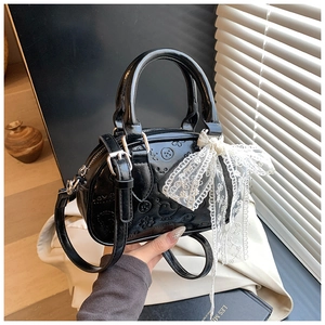 Detail of black embossed Boston bag with cute patterns and white lace bow decoration