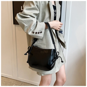 Modella che indossa una borsa a secchiello in pelle lucida in un interno minimalista