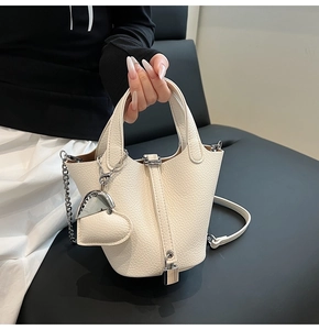 Detail of lychee textured leather bucket bag with silver lock and metal charms decoration