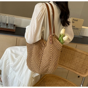 Chic woven tote bag with brown leather straps shown in a relaxed holiday lifestyle setting