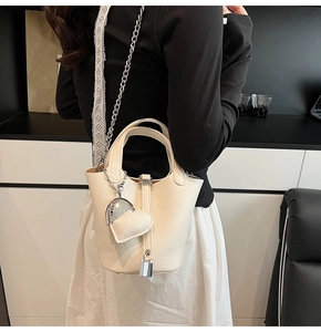 Detail of creamy white litchi grain bucket bag with silver heart charm and lock