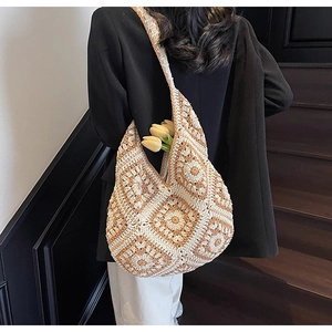 Detail of hand-woven tote bag with floral knit pattern carried on shoulder