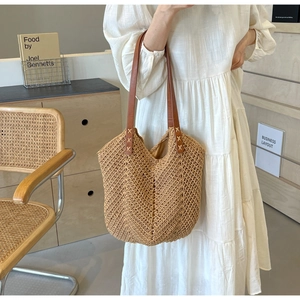 Close-up of woven straw tote bag with V-shaped pattern and leather strap cross-stitch detail