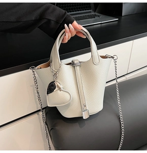 Detail of lychee pattern cream bucket bag featuring silver heart charm and metal padlock