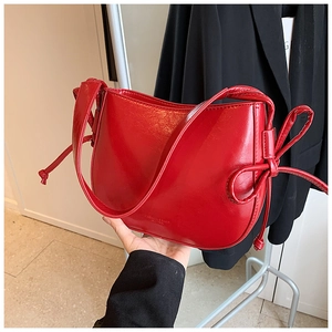 Dettaglio della borsa a secchiello rossa in pelle cerata con nodi e logo impresso