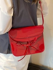 Glossy red faux leather ballet-style crossbody bag with chic bow accent on front flap