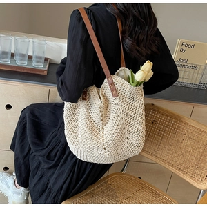 Detail of cream crochet tote bag featuring durable brown leather straps and cross-stitching