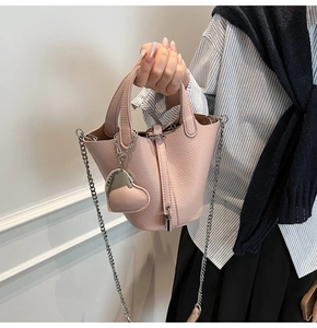 Pink lychee grain leather bucket bag with silver chain strap and heart charm detail