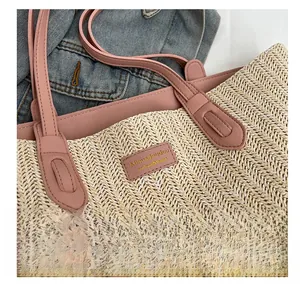 Close-up of woven straw tote bag with pink leather handle and embossed logo tag