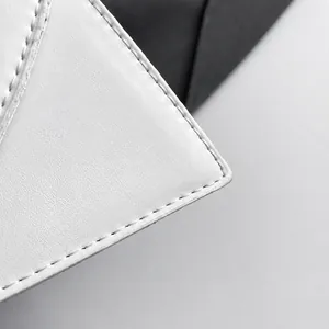 Detailansicht von weißem Leder mit Litschi-Muster und präzisen Nähten an der Handtasche