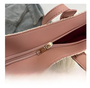 Detail view of gold metal zipper and leather trim on a minimalist woven straw tote bag