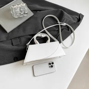 Detailansicht einer weißen geometrischen Lederhandtasche mit geschwungenem silbernem Metallgriff
