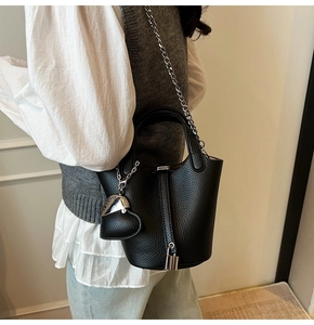 Detail shot of black litchi pattern bucket bag featuring silver chain and metal lock charm