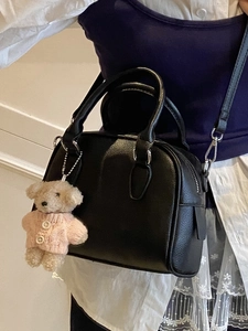 Black pebbled leather bowling bag with top handles and a cute teddy bear charm