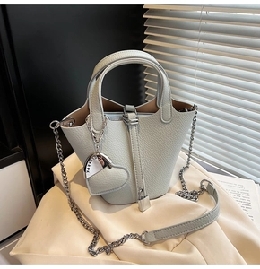 Close-up of light blue lychee pattern leather bucket bag with silver chain strap and pendant
