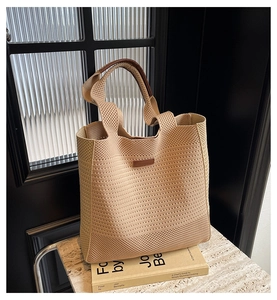 Close-up of beige woven tote bag with brown faux leather handles and hollow knit texture