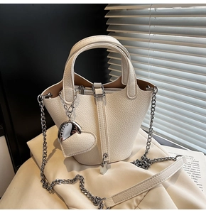 Detailed macro view of white lychee pattern leather bucket bag with silver heart charm