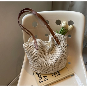 Detail of woven tote bag with brown leather handle and white tulips on a beige chair