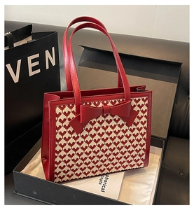 Close-up of red and white woven heart texture with bow detail in a premium black gift box