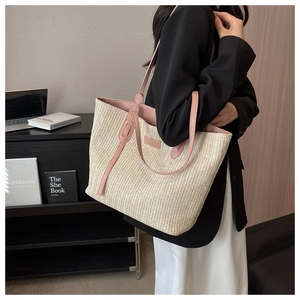 Close-up of woven straw tote bag with pink leather trim and natural texture detail