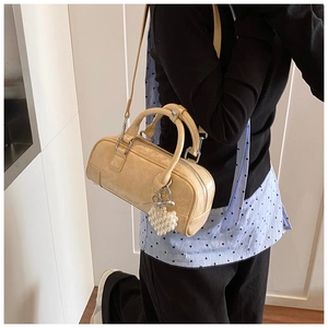 Detail view of beige bowling bag with pearl heart pendant and wrinkled leather texture