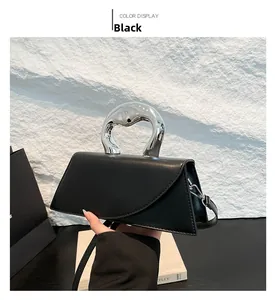 Détail du sac à main noir avec poignée en métal argenté et texture en cuir mat