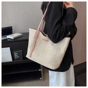 Detail of a large woven tote bag with pink leather trim and straps shown in a lifestyle setting