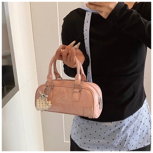 Pink Boston bag close-up with pearl heart charm and textured faux leather finish