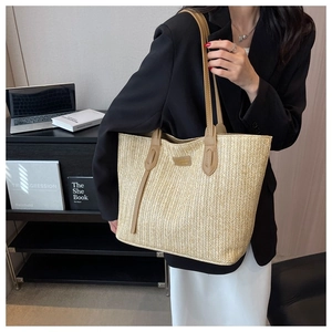 Close-up of beige woven tote bag with leather straps and metal logo for office fashion