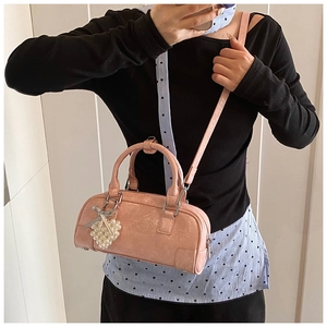 Detail of pink crinkled patent leather bag with pearl heart charm and silver bow