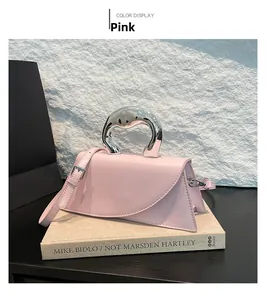 Détail du sac à main en cuir rose avec poignée en métal argenté sur fond de livre d'art