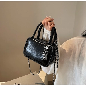 Dettaglio della borsa boston in vernice nera lucida con catena d'argento e charm