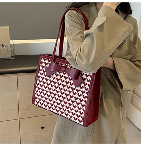Close-up of red and white woven heart pattern tote bag with large leather bow detail