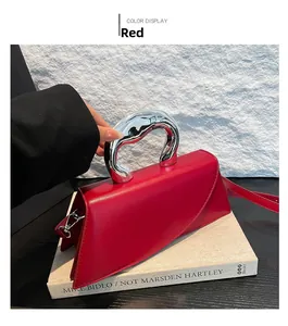 Détail du sac à main rouge en cuir avec poignée sculpturale en métal argenté élégante
