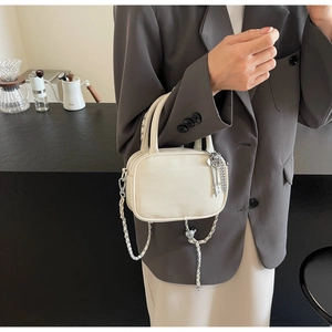 Dettaglio mini borsa crema effetto coccodrillo con catena argento e ciondolo chiave