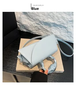 Détail du petit sac carré bleu clair avec poignée anneau argentée et bandoulière amovible