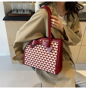 Detailed side view of tote bag with red bow and heart pattern on a khaki trench coat