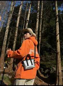 Outdoor-Szene mit einer silbernen Metallic-Tyvek-Tasche und einer orangefarbenen Jacke