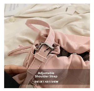 Detail view of pink glossy bucket bag with adjustable buckle strap and pleated design