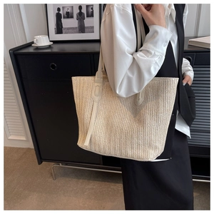 Detail shot of a beige woven tote bag styled in a minimalist interior setting