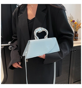 Détail d'un sac à main géométrique bleu clair avec poignée argentée porté par modèle